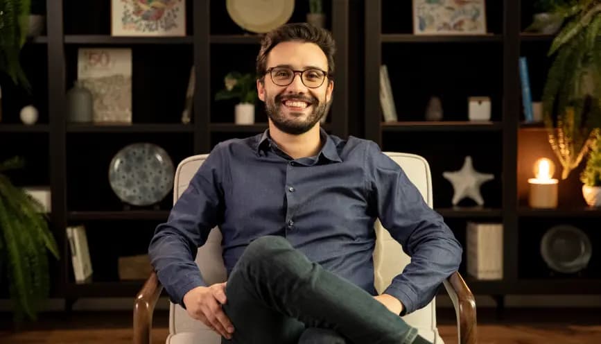 Dr. João Brunhara, responsável técnico da Cuidei, sentado diante de uma estante